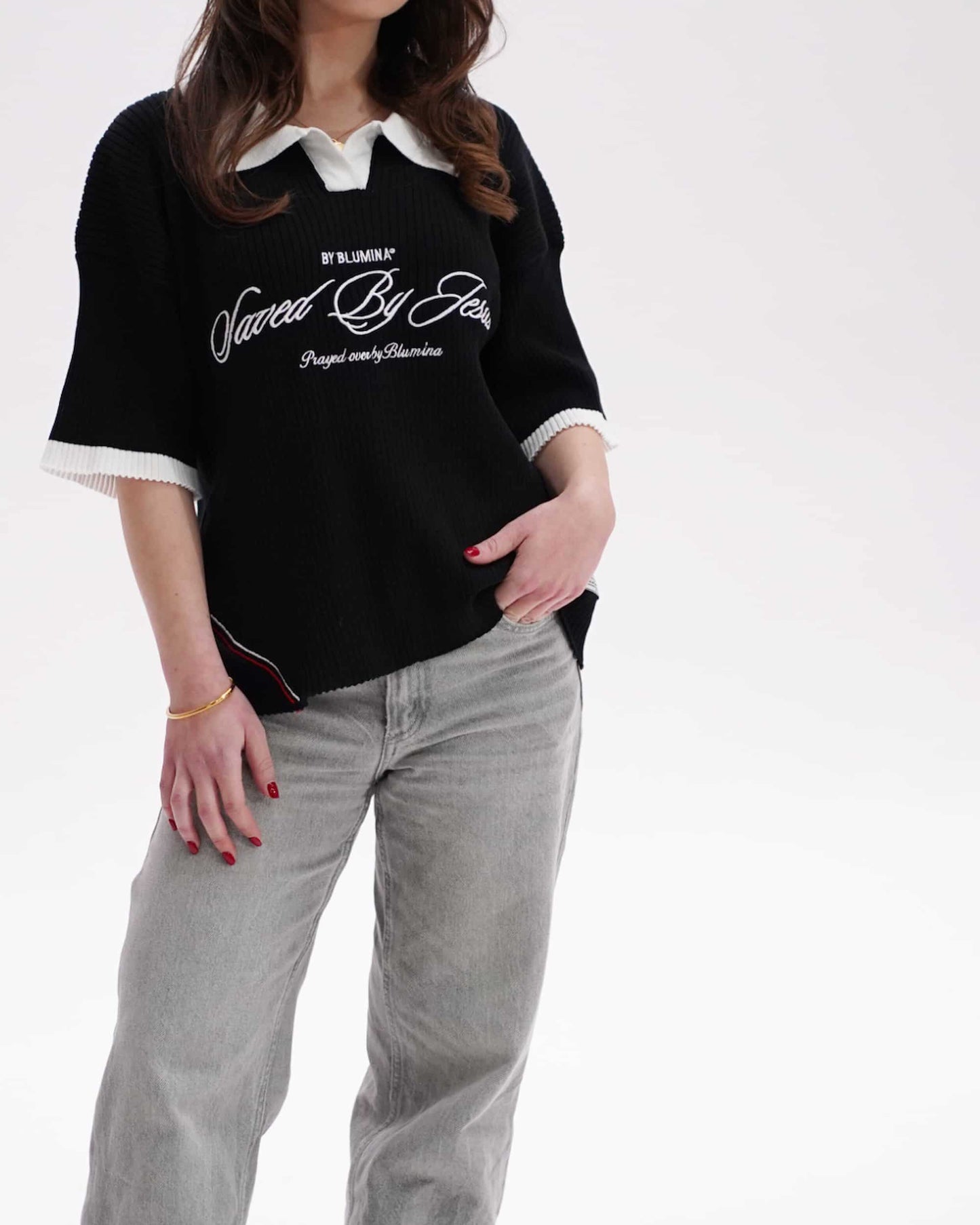 Person wearing a black t-shirt with white text and light gray pants on a white background