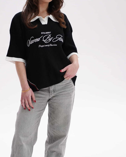 Person wearing a black t-shirt with white text and light gray pants on a white background