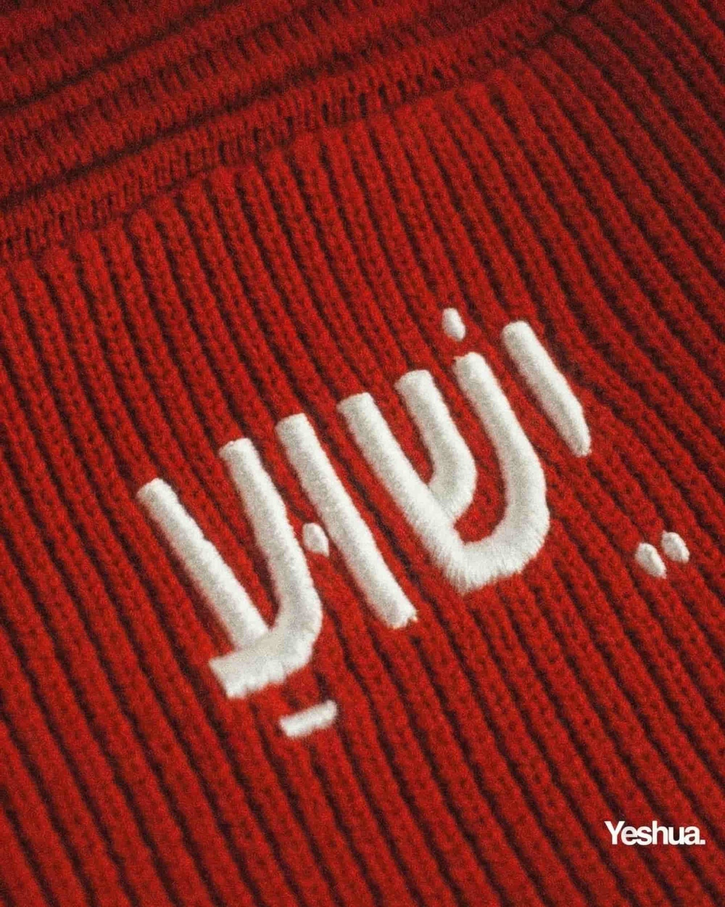 Red fabric with white embroidered text 'Yeshua' on a close-up view